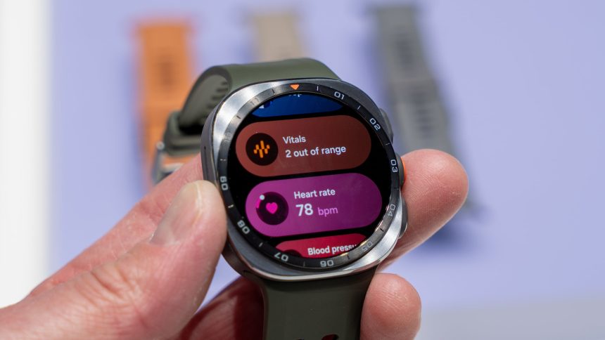 Photo officielle de la Samsung Galaxy Watch 9 tenue en main, écran affichant les widgets santé (vitals, fréquence cardiaque, tension)