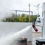 Robot humanoïde tenant un extincteur et déchargeant de la poudre sur un feu réel lors de l'exercice de lutte contre l'incendie des World Humanoid Robot Games à Pékin