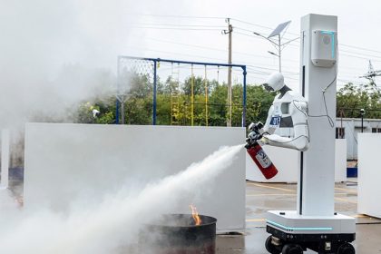 Robot humanoïde tenant un extincteur et déchargeant de la poudre sur un feu réel lors de l'exercice de lutte contre l'incendie des World Humanoid Robot Games à Pékin