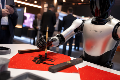 Robot humanoïde AgiBot A3 écrivant de la calligraphie au pinceau sur papier rouge à l'IFA Berlin 2026, plan rapproché net